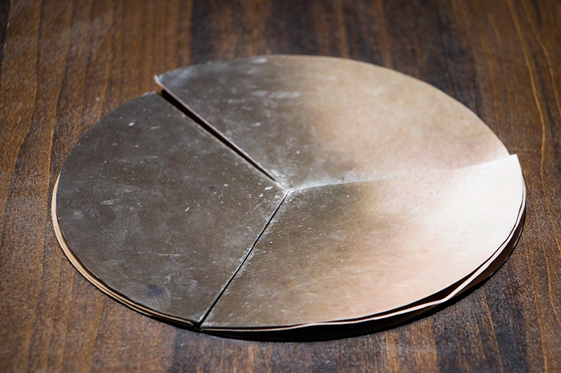 Circular non-linear artist book with flesh imagery on a wooden table.