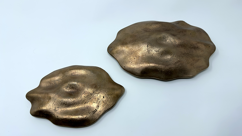 Two bronze fog forms on a white background, the bronze has a dull shine and is a reddish gold color.