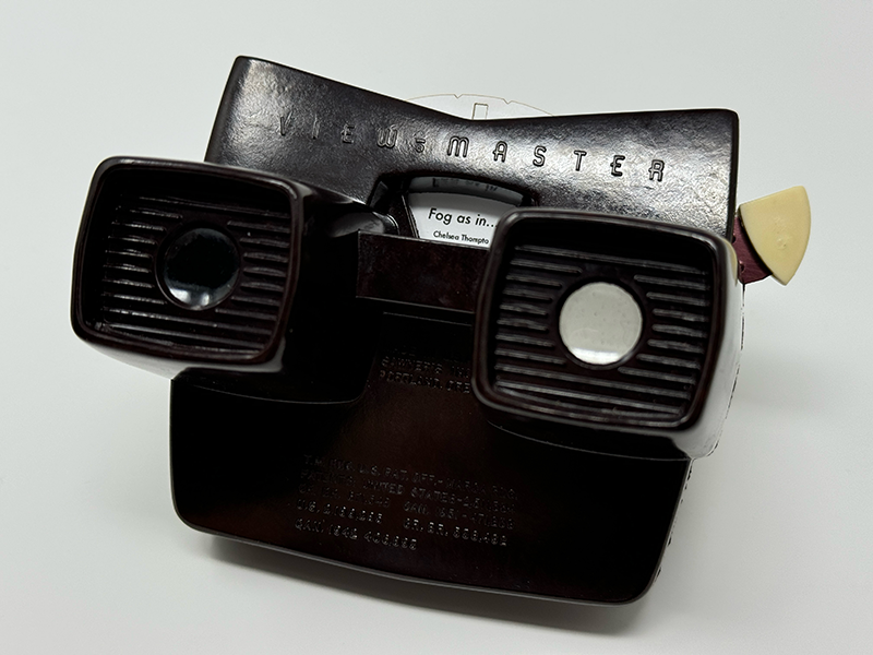 A vintage brown View-Master device loaded with a white disc titled 'Fog as in...'.